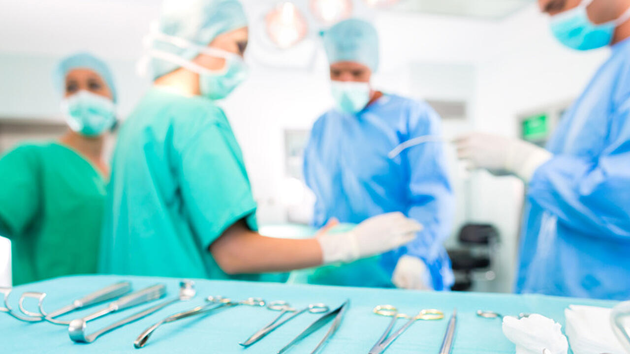 Ärzte und Schwestern am Operationstisch, der sich im Vordergrund mit vielen Instrumenten darauf befindet